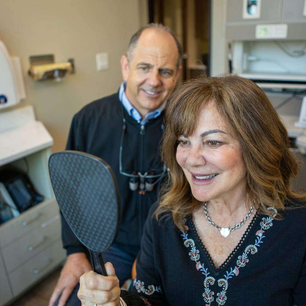 Dr. Slaman with a happy smiling patient looking in the mirror