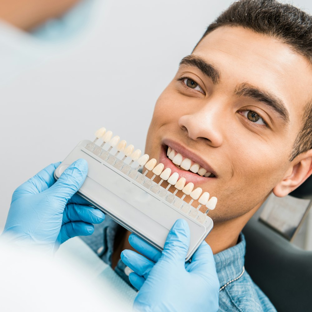 Close-up of patient's mouth comparing natural teeth to porcelain veneers before cosmetic dentistry procedure